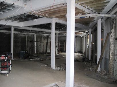 A large empty room with white pillars and a ladder.