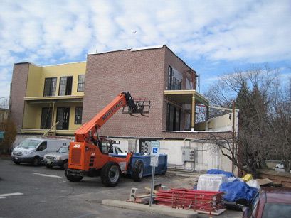 An orange forklift is parked in front of a building under construction