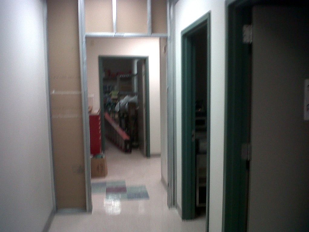 A hallway with a green door and a white wall