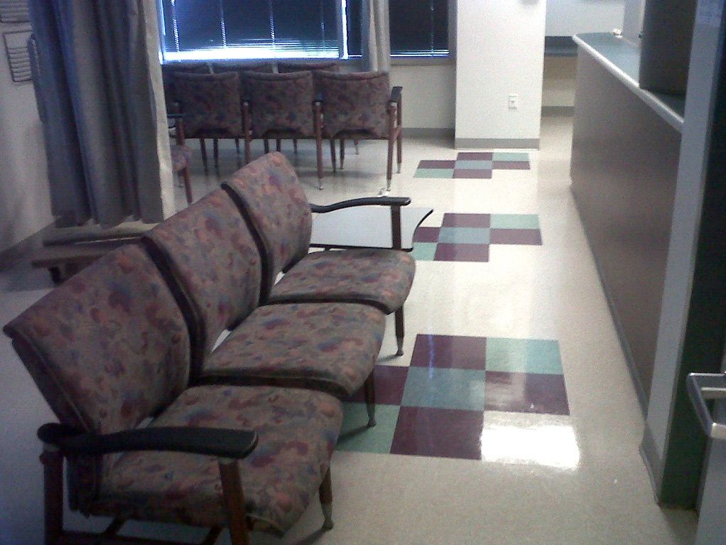 A row of chairs in a hallway with a checkered floor