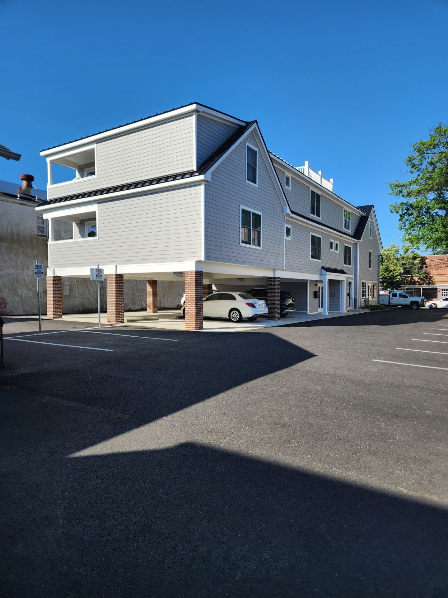 A white car is parked in front of a large building.