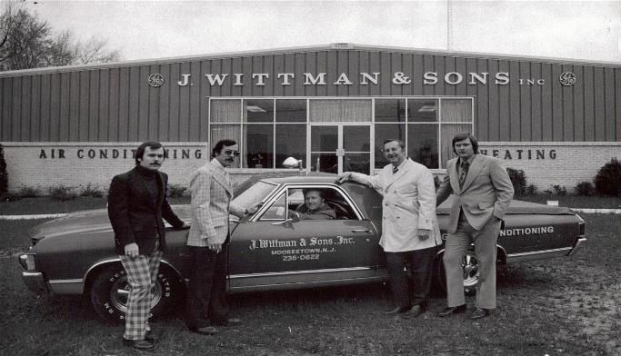 A group of men standing in front of a building that says J Wittman & Sons