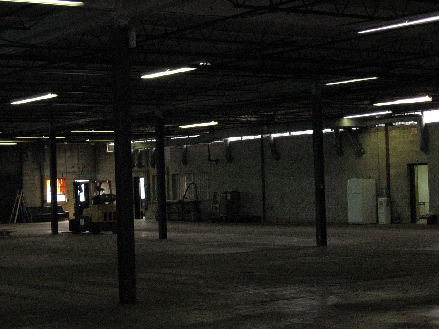 An empty warehouse with a forklift in the middle.