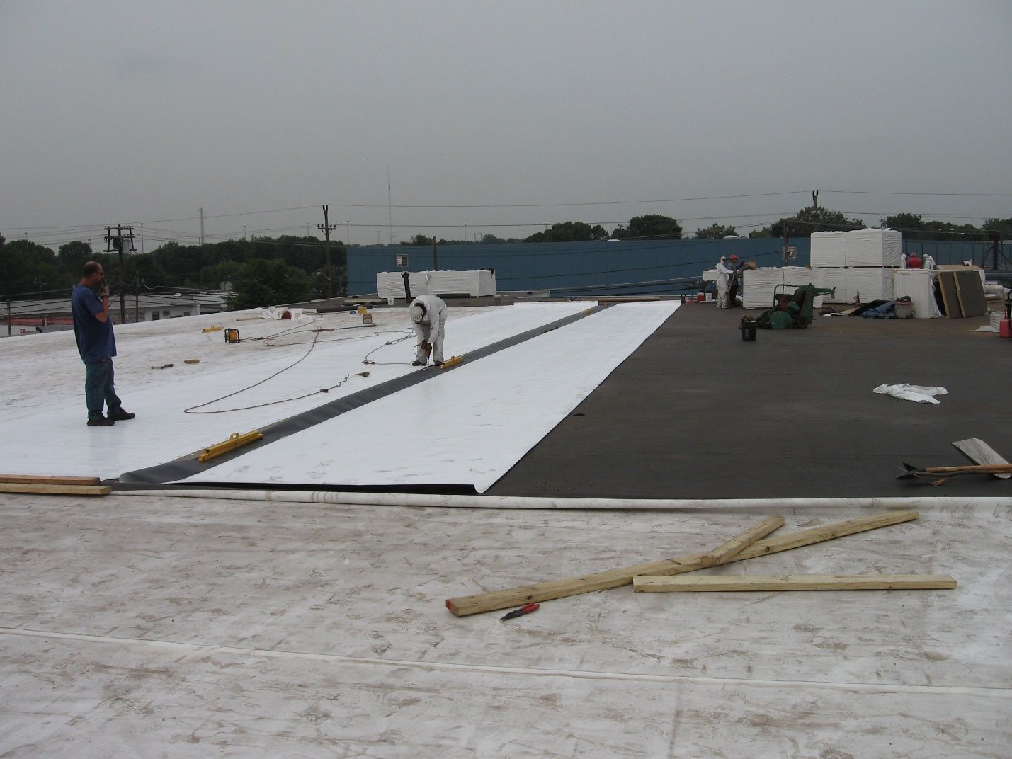 A man is standing on top of a white roof.