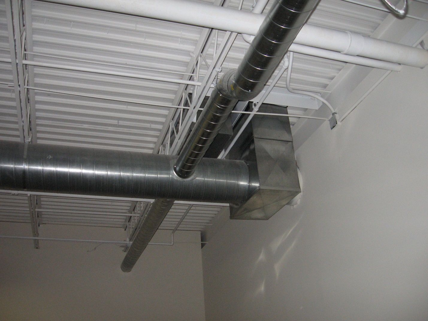 A metal pipe is hanging from the ceiling of a building.