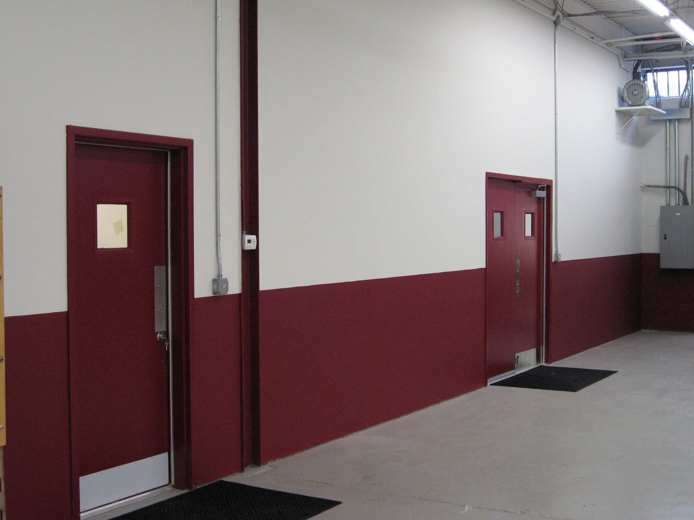 A hallway with red and white walls and red doors.