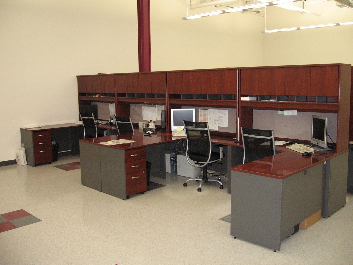 A row of cubicles with a computer on each desk.
