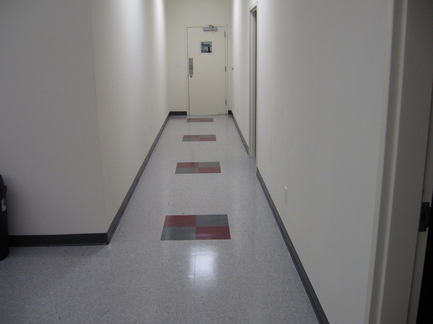 A long hallway with a red and gray tile floor.