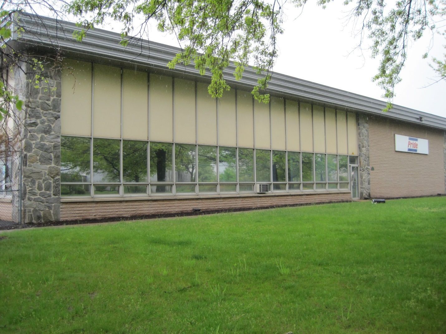 A large building with a lot of windows is sitting on top of a lush green field.