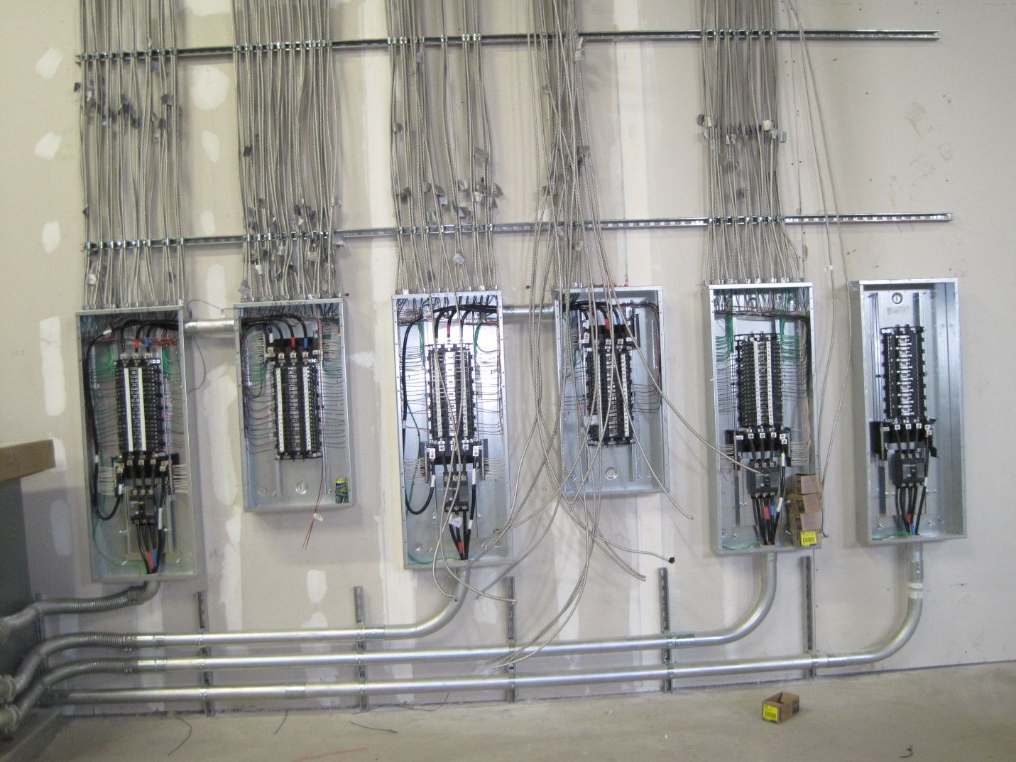 A row of electrical panels are lined up on a wall.