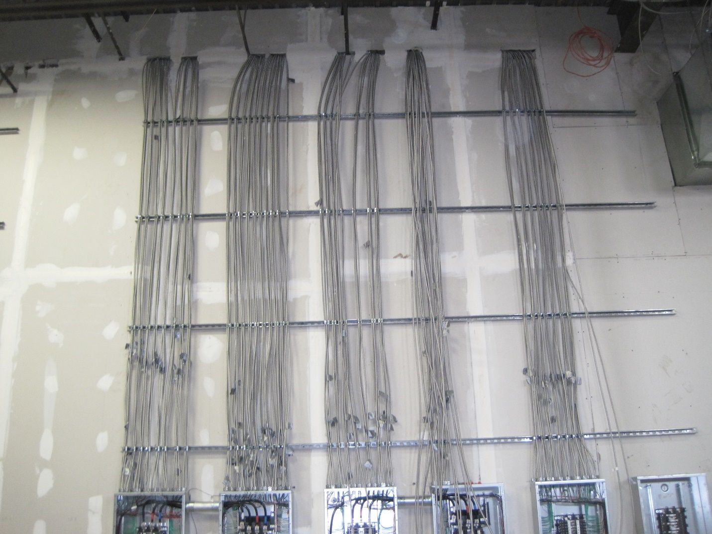 A wall with a bunch of wires hanging from it.