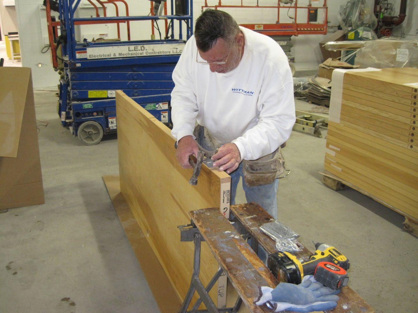 A man in a white shirt is working on a piece of wood.