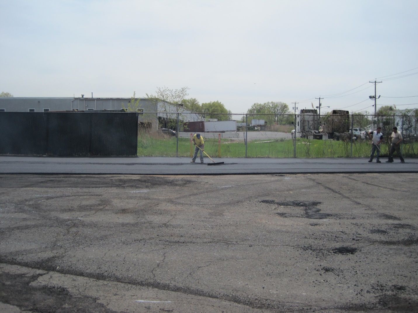 A man in a yellow vest is walking across an empty parking lot.