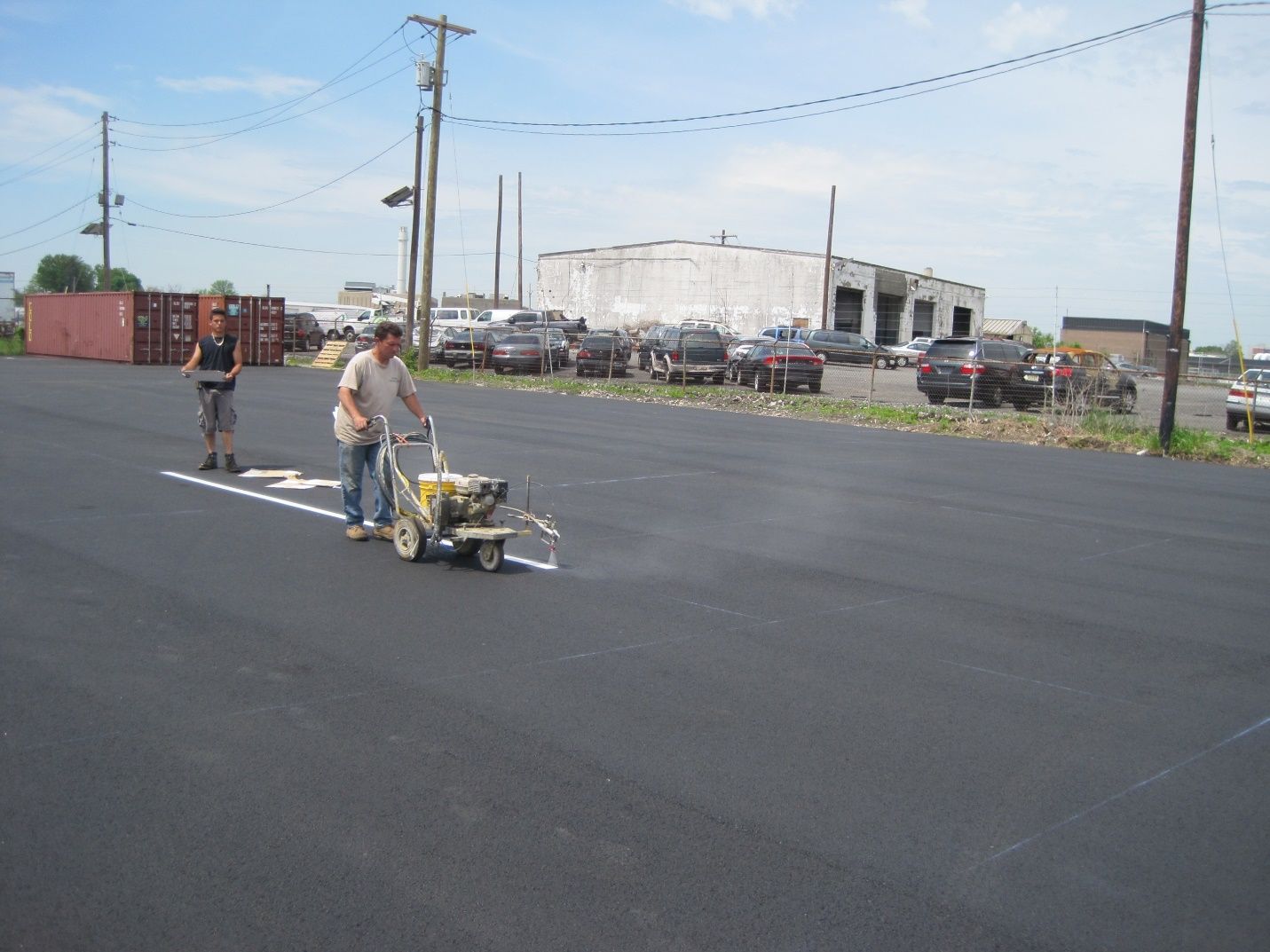 A man is using a machine to paint a white line on the road.