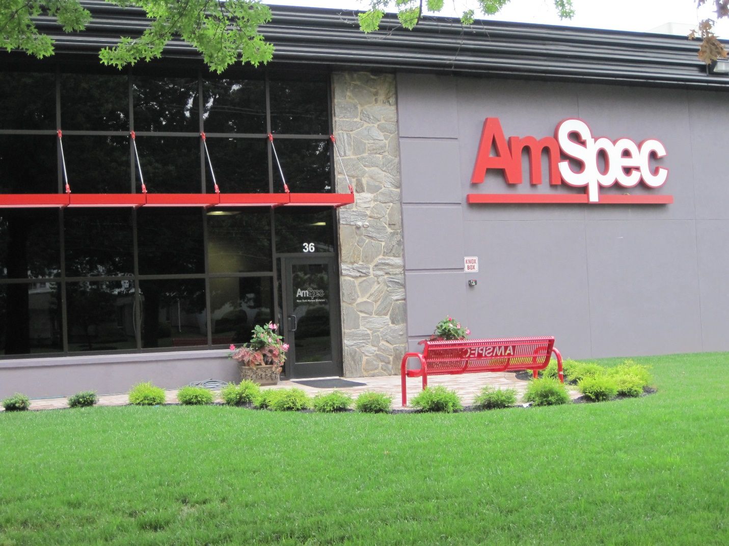 An am spec building with a red bench in front of it.