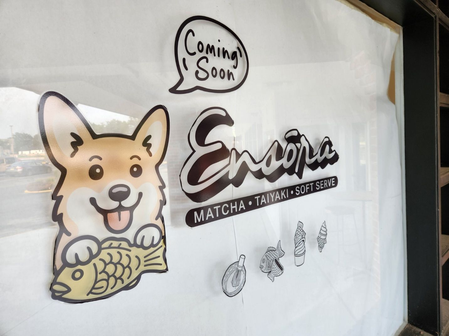 A Coming Soon sign for Ensora, a shop with a corgi mascot holding a fish-shaped pastry.