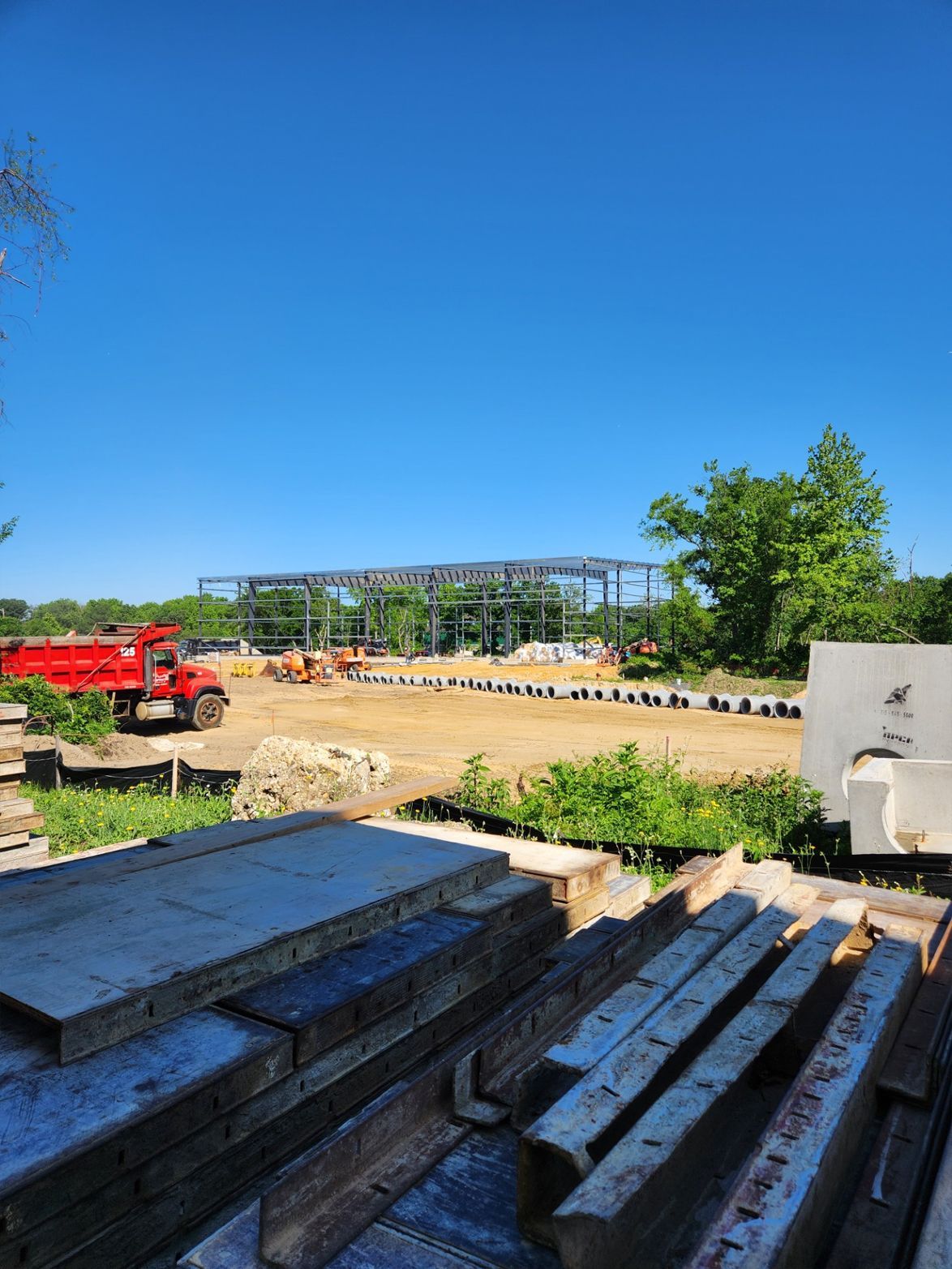 Construction site with steel frame, red truck, and clear blue sky.