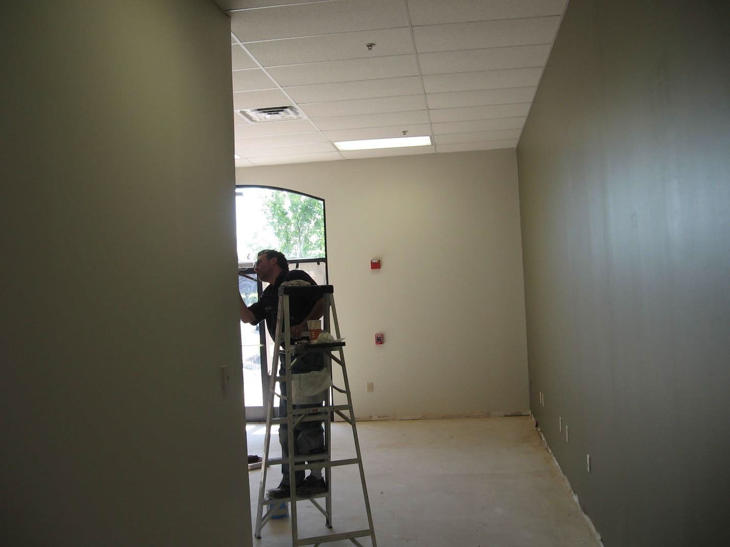 A man is standing on a ladder in an empty room