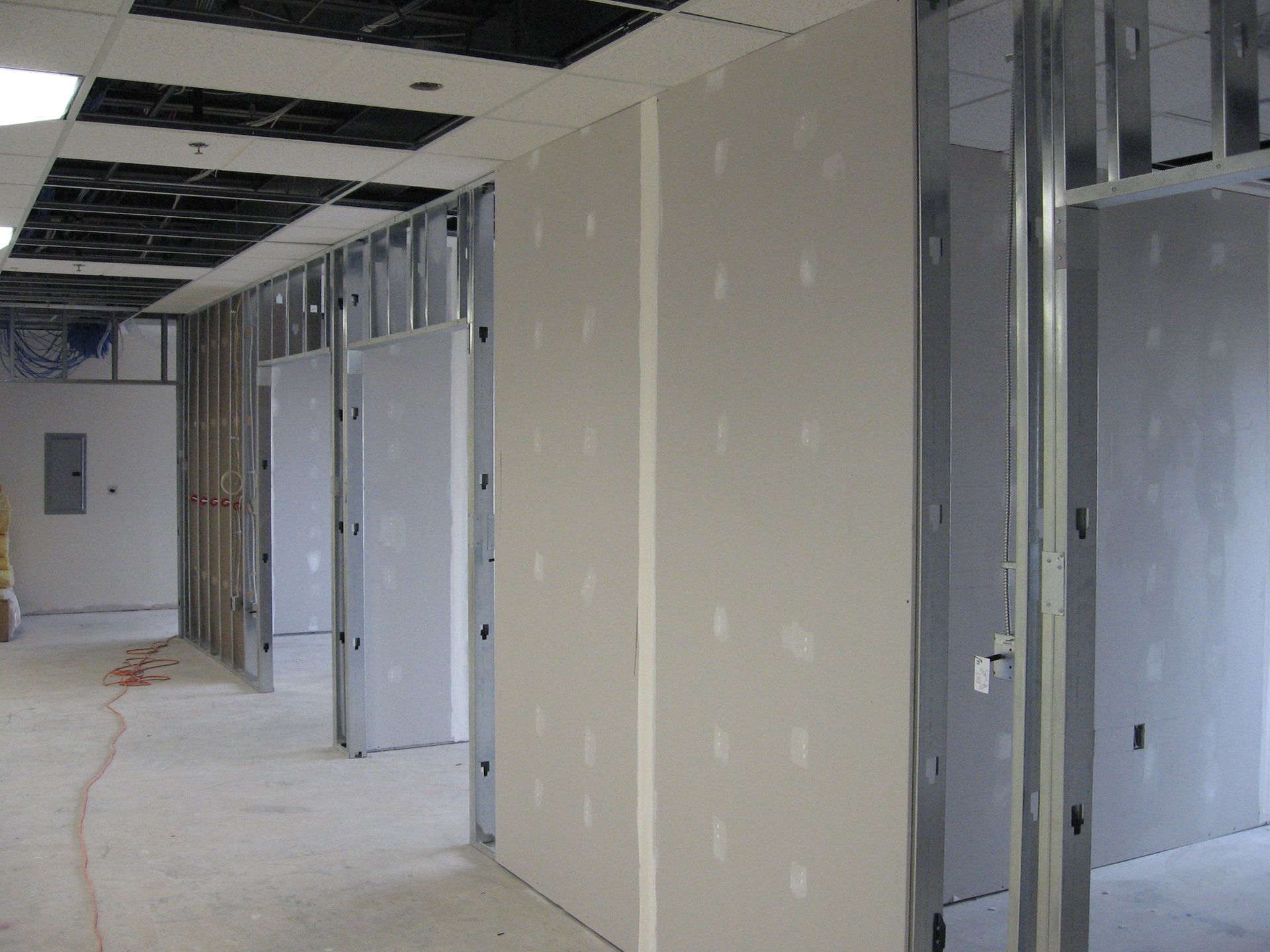 A hallway in a building under construction with a ladder in the corner