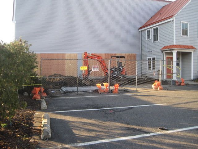 A white house with a red roof is being remodeled.