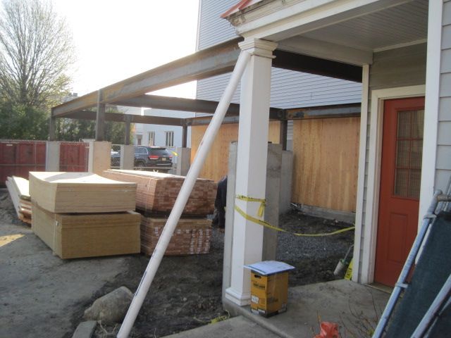 A stack of boxes sits on the ground in front of a house under construction.