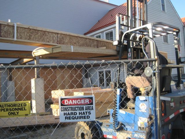 A construction site with a forklift and a sign that says danger construction area hard hats required.