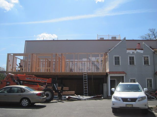 A white car is parked in front of a building under construction.