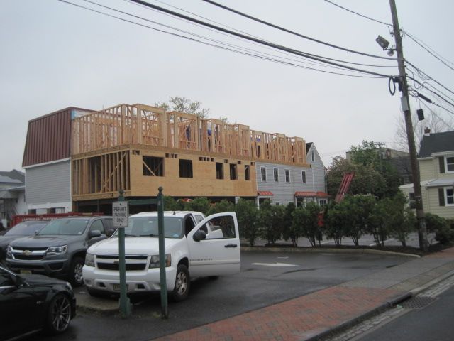 A white van is parked in front of a building under construction.