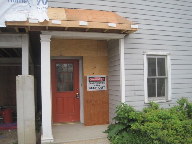 A house under construction with a danger sign on the door.