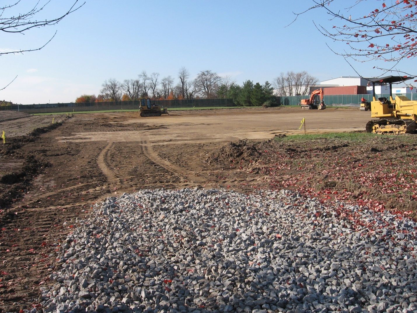 A yellow bulldozer is moving gravel in a field.