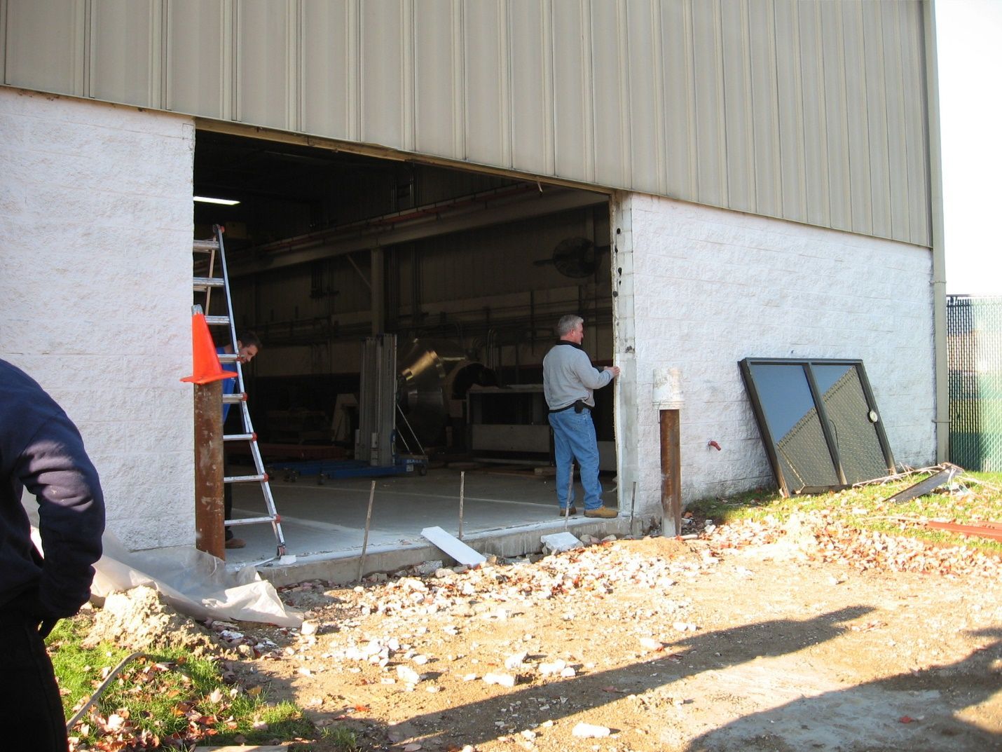 A man standing in front of a building with a ladder.