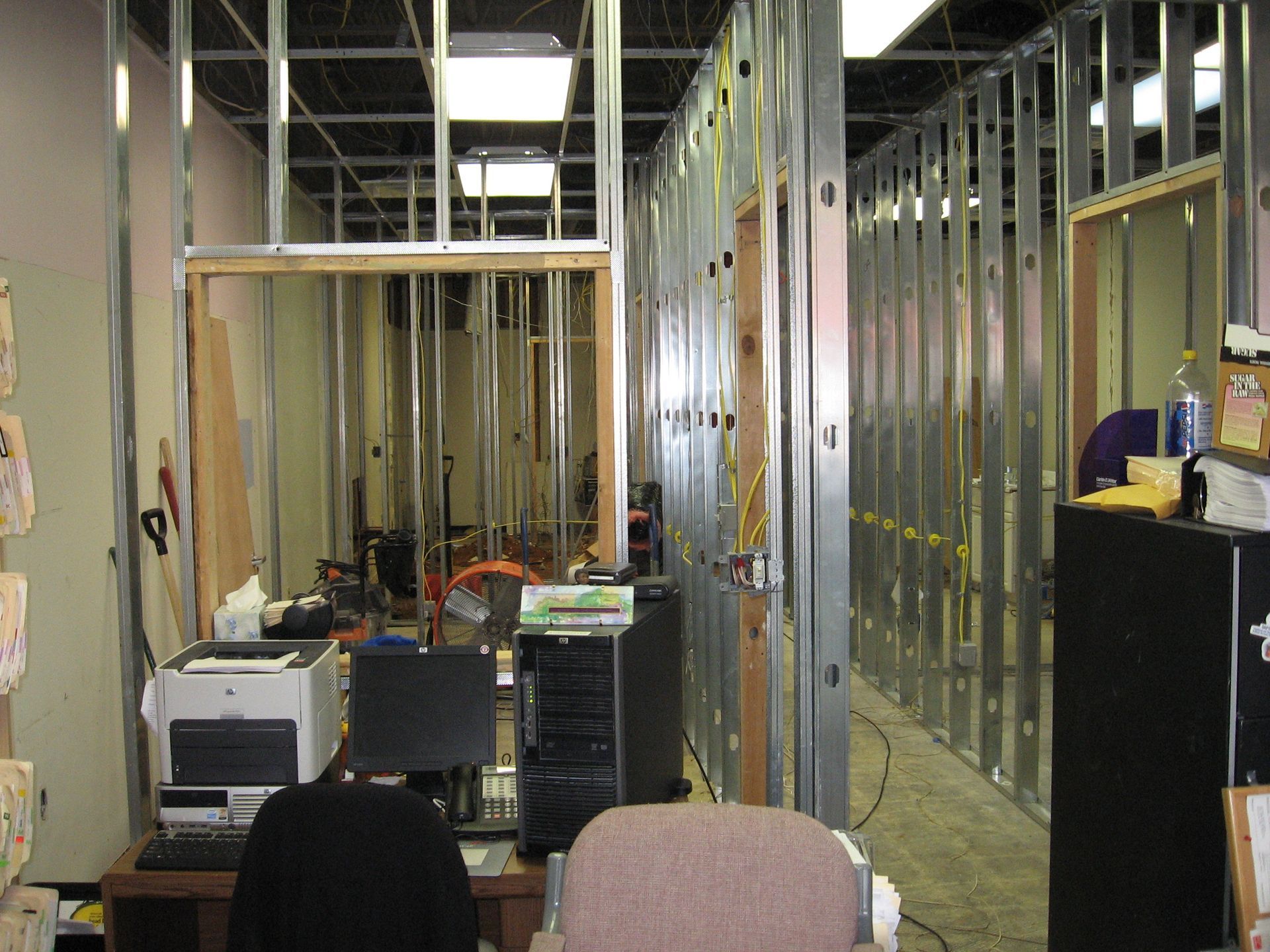 An office under construction with a printer and a chair