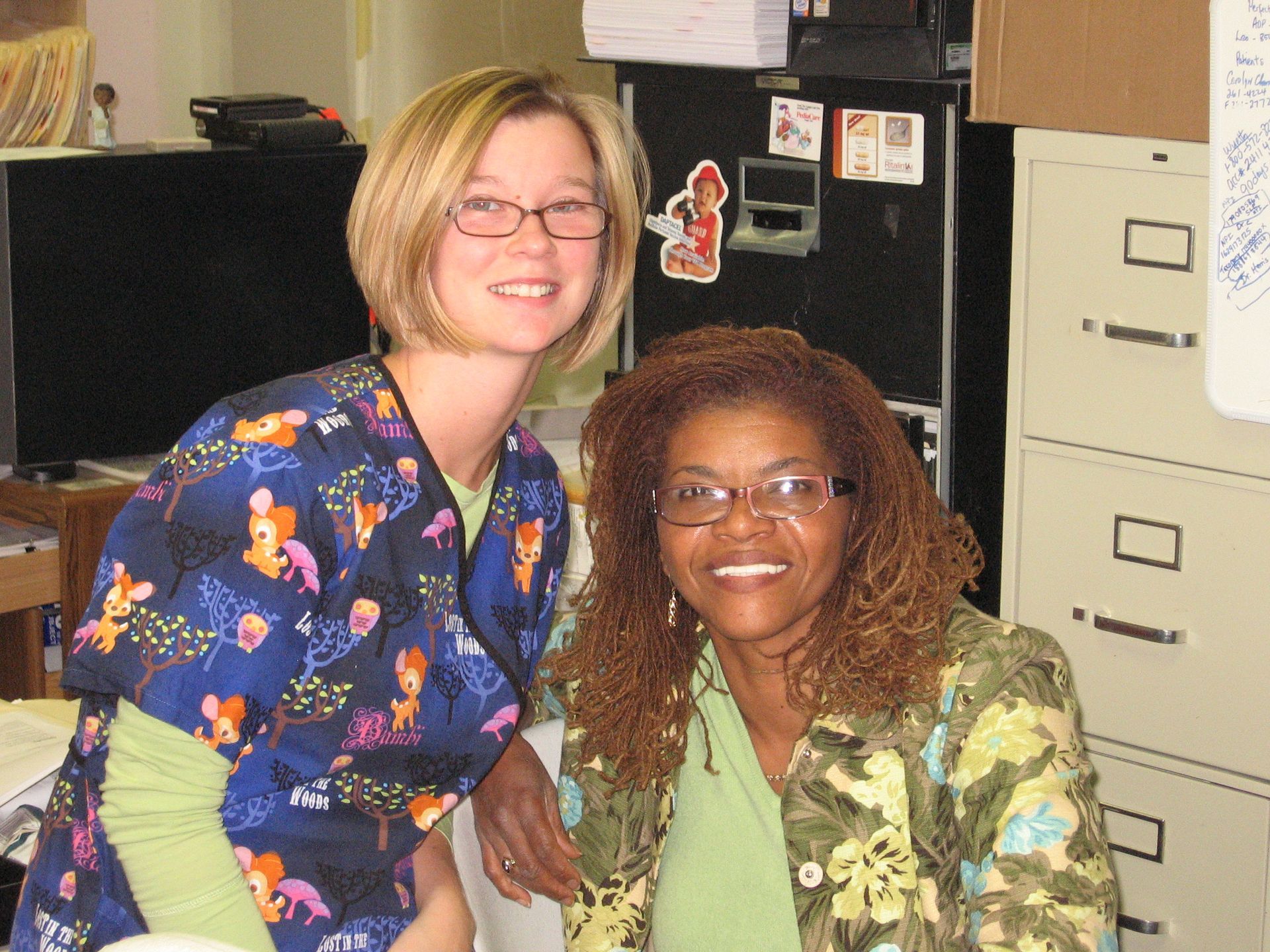 Two women are posing for a picture in front of a filing cabinet