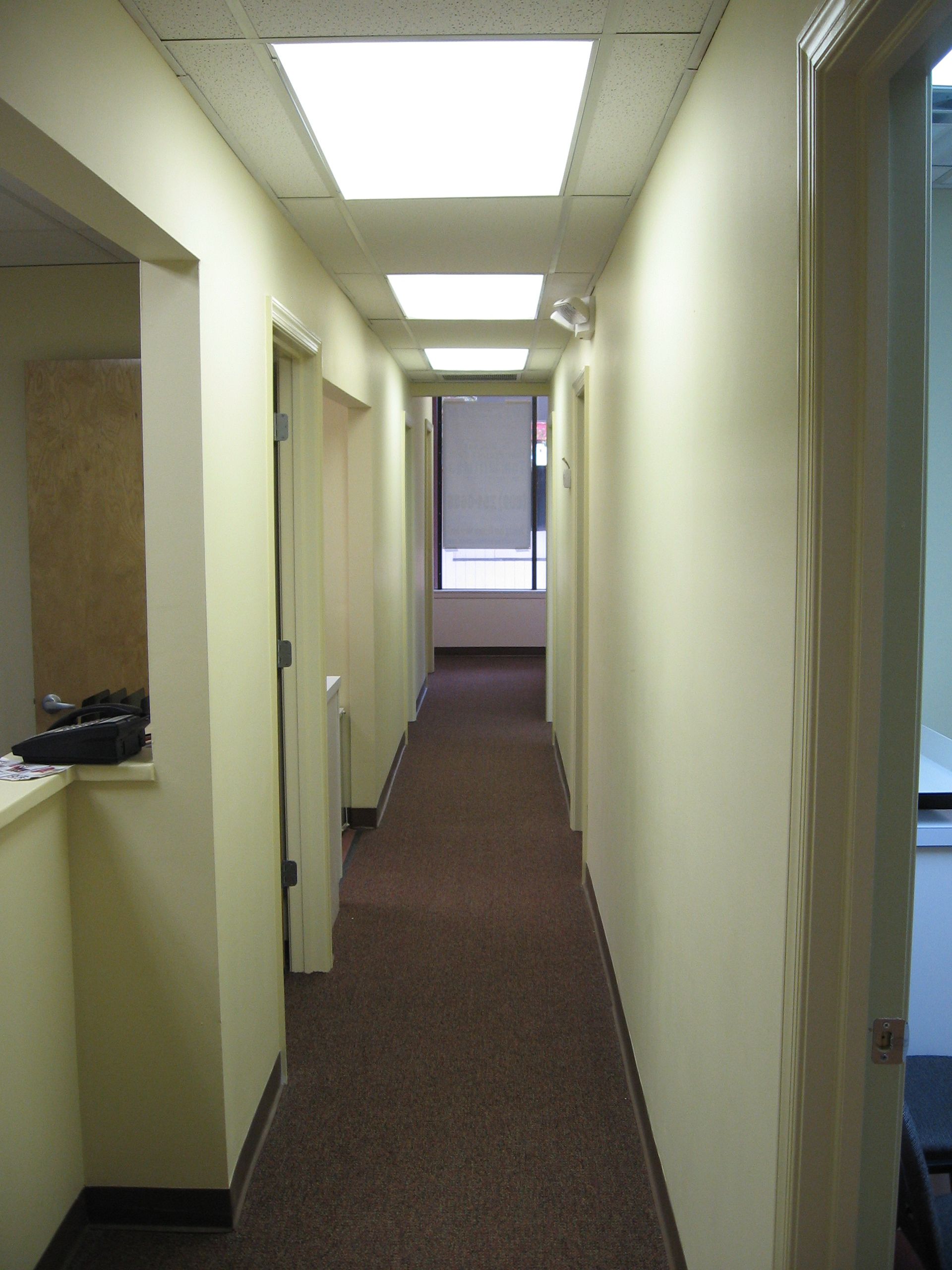 A long hallway with white walls and brown carpet