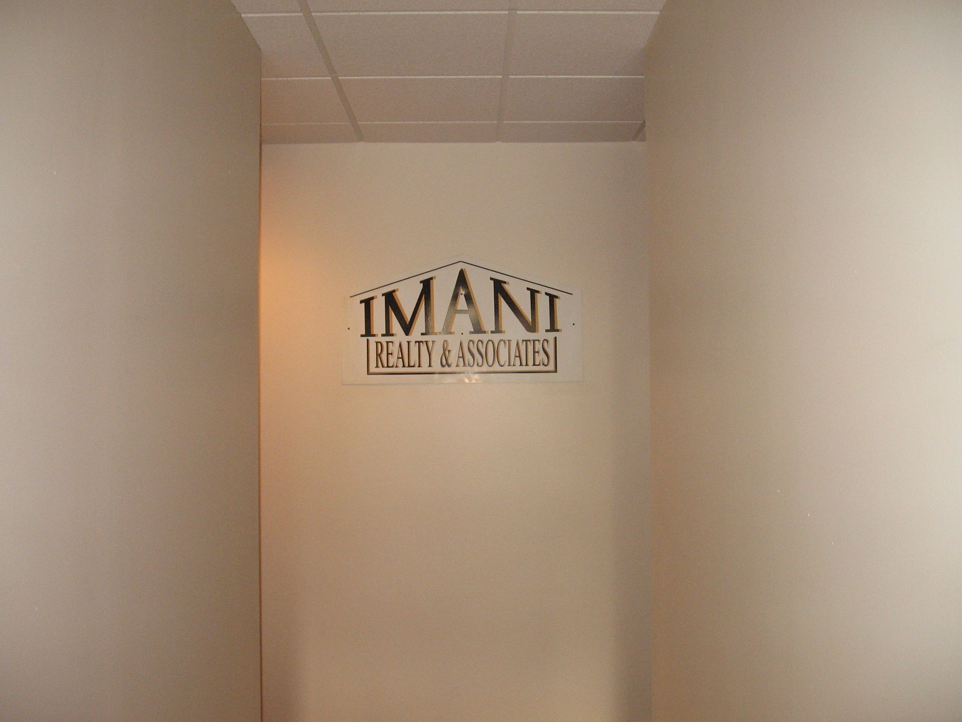 A sign on a wall that says Imani Realty Associates