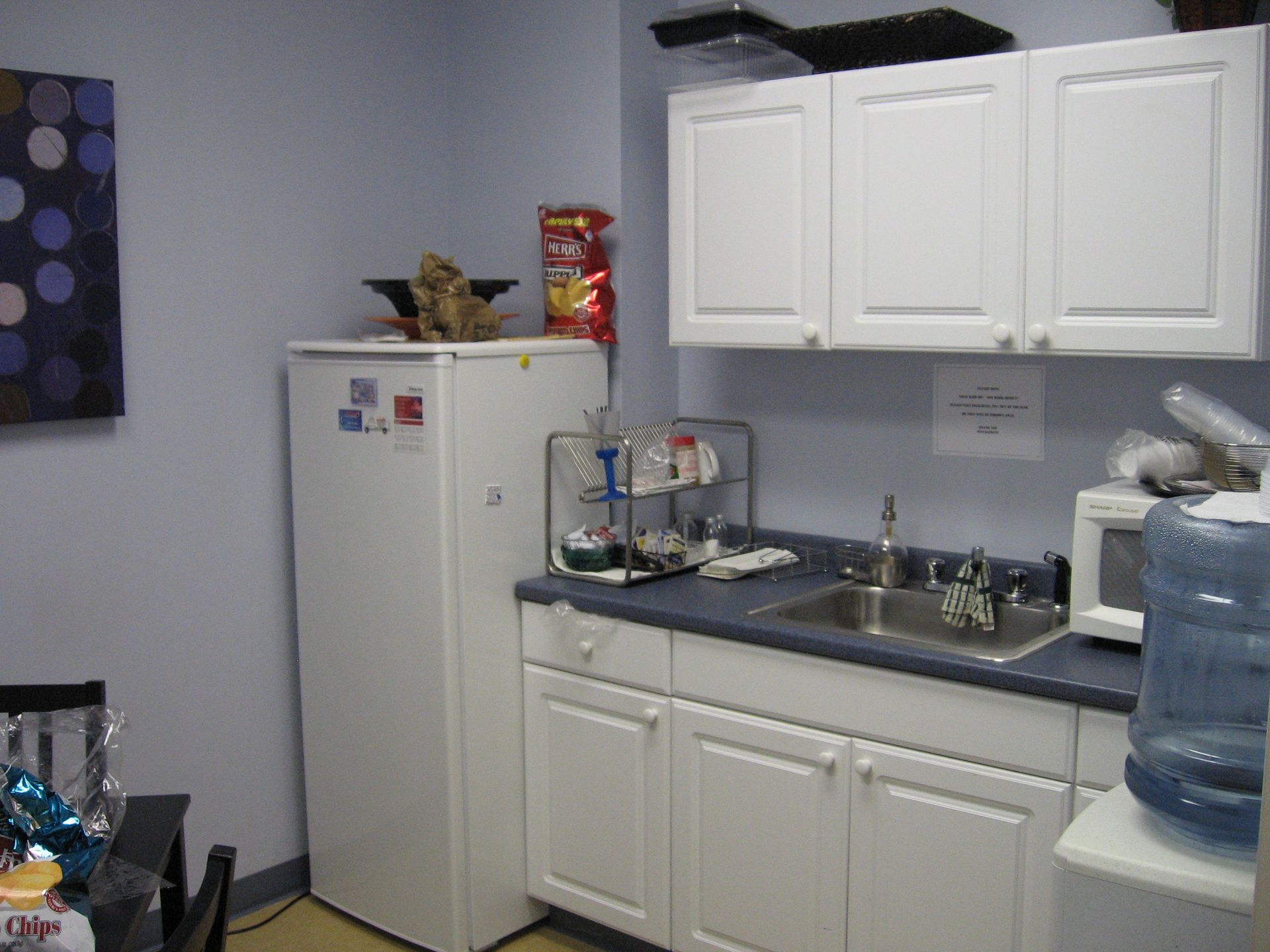 A kitchen with white cabinets a sink and a refrigerator