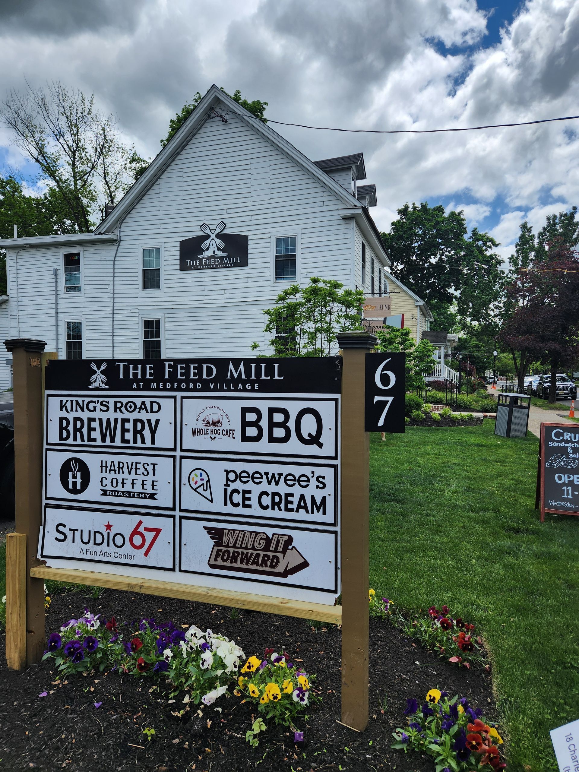 A sign for The Feed Mill Brewery is in front of a white building.