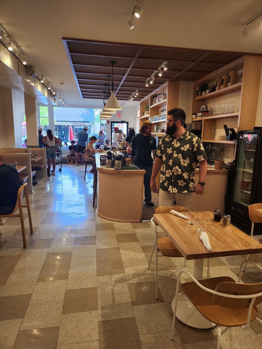 A man in a Hawaiian shirt is standing in a restaurant.
