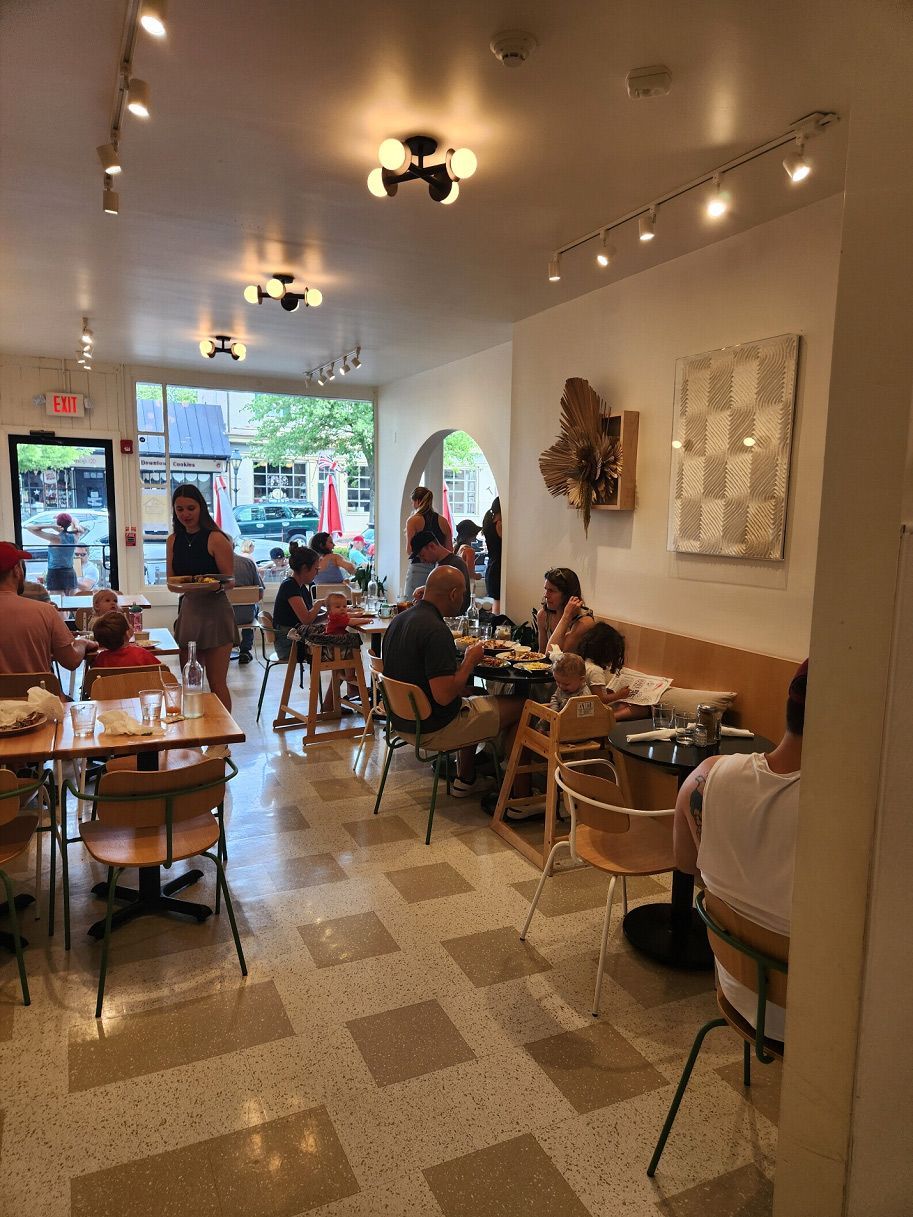 A restaurant filled with people sitting at tables and chairs.