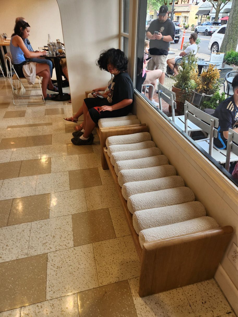 A woman sits on a bench in front of a window in a restaurant