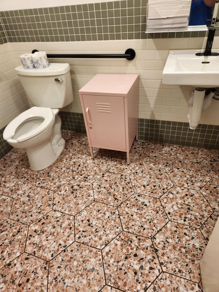 A bathroom with a toilet, sink, and pink locker.