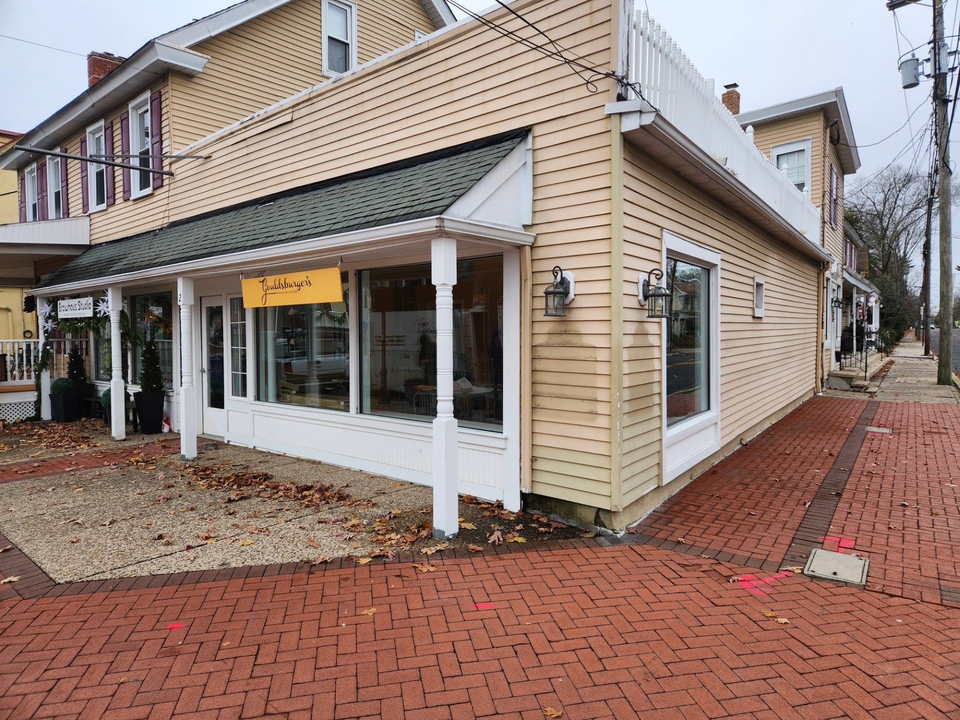 A yellow and white building with a brick sidewalk in front of it.