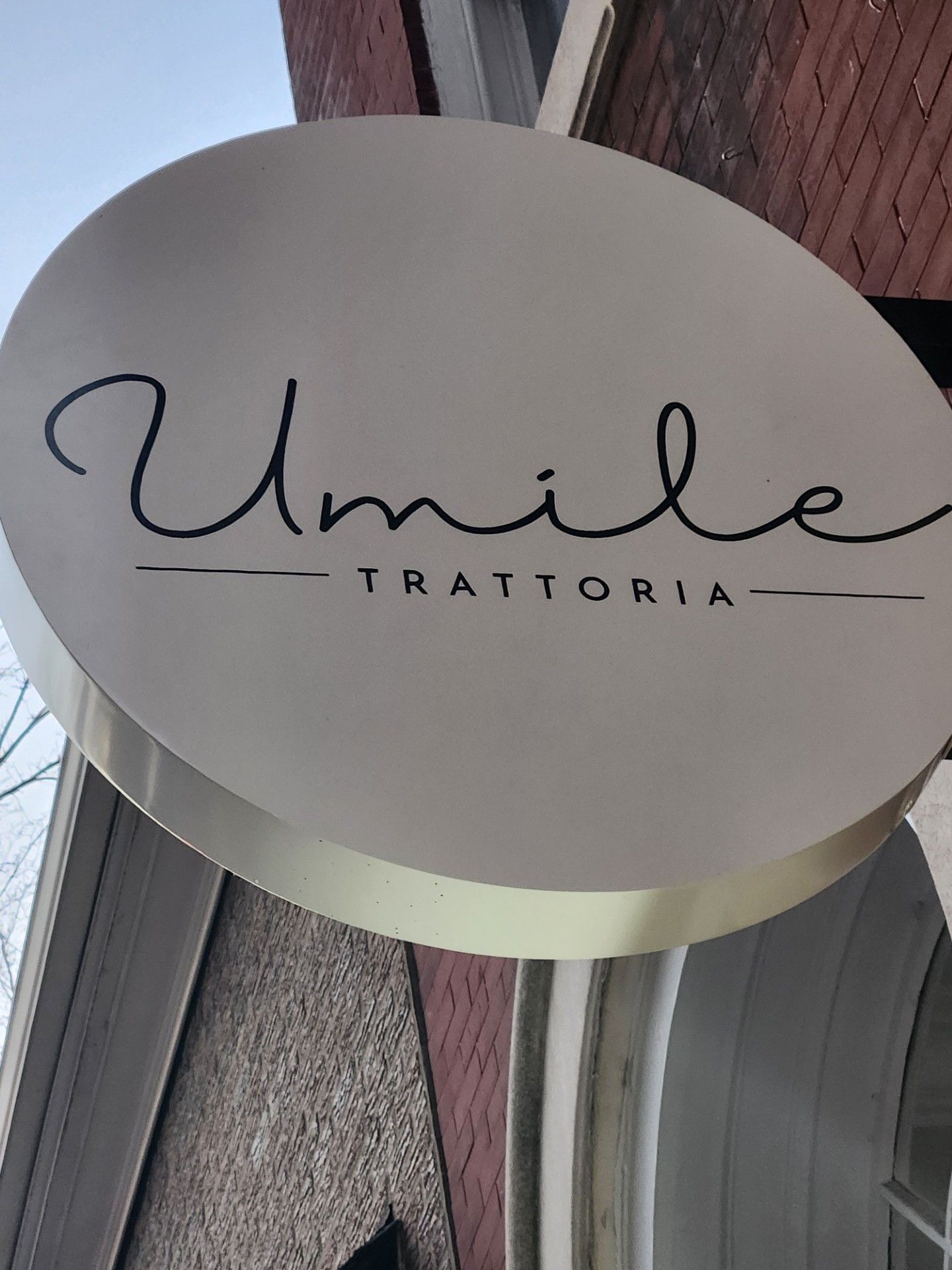 A white sign that says Umile Trattoria on it
