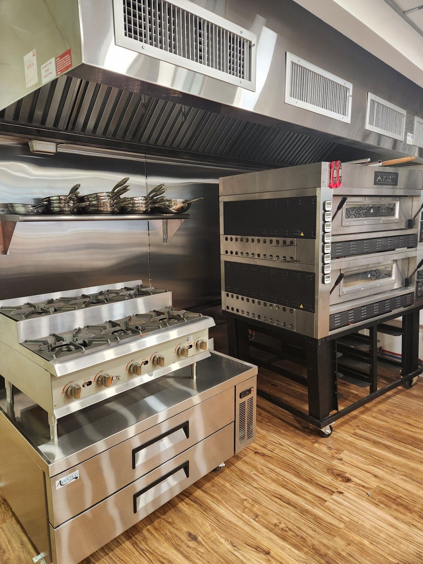 A kitchen with stainless steel appliances and a pizza oven.