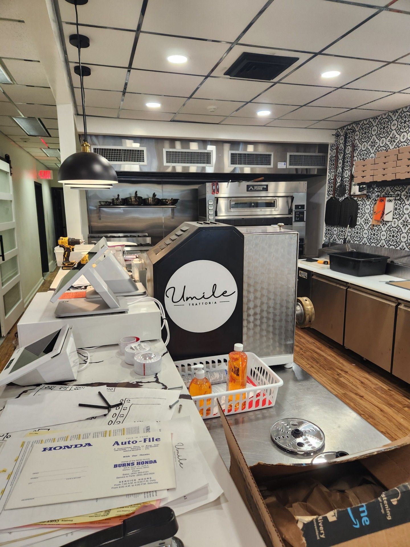 The inside of a restaurant with a counter and a pizza oven.
