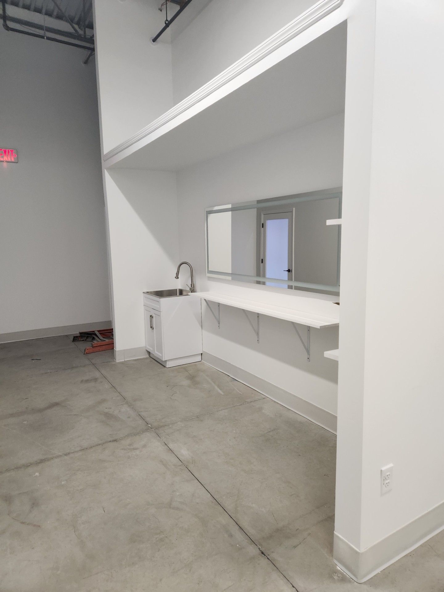 An empty room with a sink and a mirror on the wall.