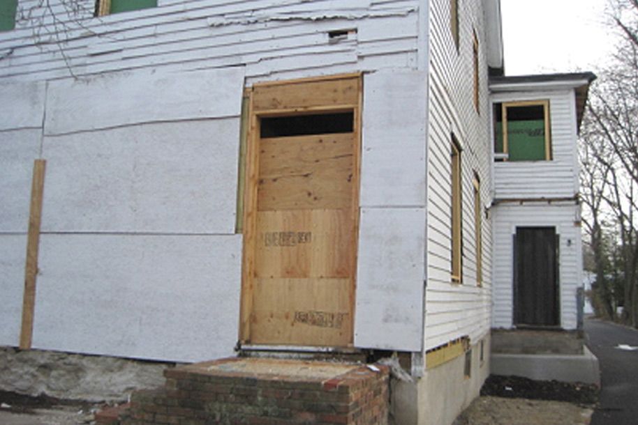 A white house with a door that is boarded up