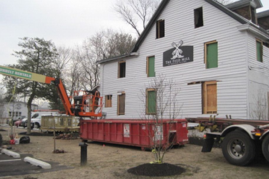 A white house with a red dumpster in front of it