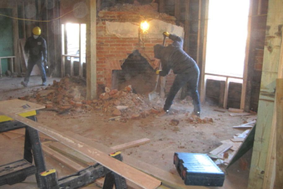 A group of construction workers are working on a brick wall in a room.