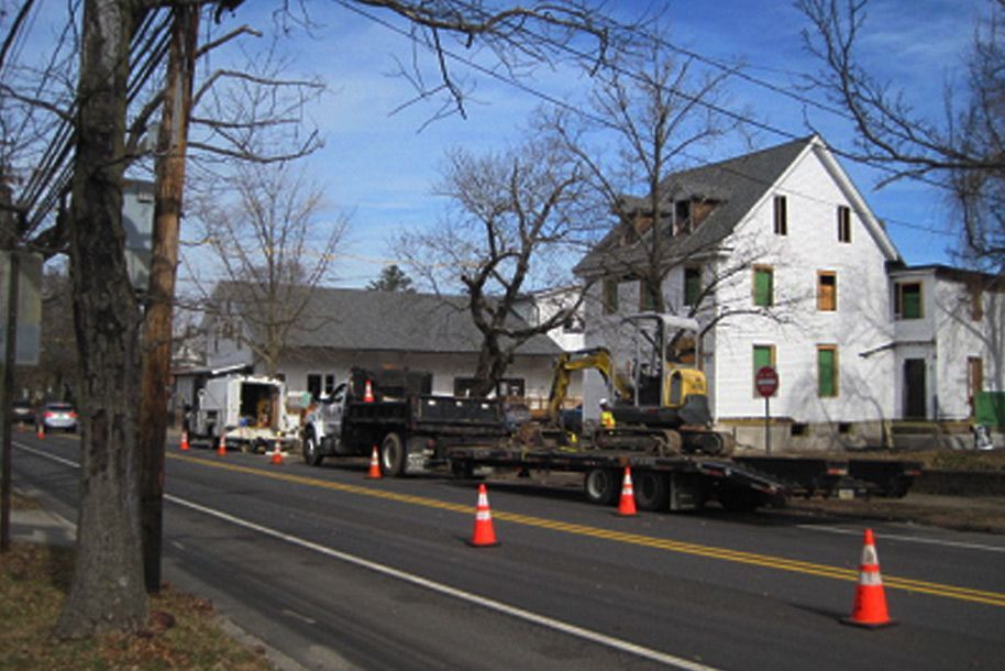 A tow truck is parked on the side of the road in front of a white house